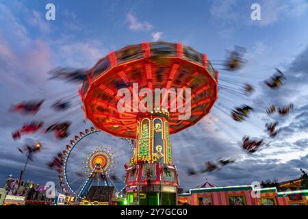 Kettenkarussell beim Oktoberfest 2024 in der Abenddämmerung, München, Bayern, Deutschland | Schaukelfahrt auf dem Oktoberfest 2024 in der Abenddämmerung, München, Bayern, Stockfoto