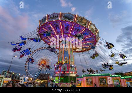 Kettenkarussell beim Oktoberfest 2024 in der Abenddämmerung, München, Bayern, Deutschland | Schaukelfahrt auf dem Oktoberfest 2024 in der Abenddämmerung, München, Bayern, Stockfoto