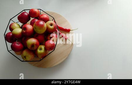 Ein farbenfroher Korb mit frischen Äpfeln und roten Chilis Stockfoto