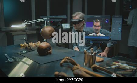Fortgeschrittenes archäologisches Labor: Archäologe in VR-Headset führt wissenschaftliche Forschung in Augmented Reality mit fossilem Schädel durch. 3D-Animation der virtuellen Anzeige mit AI-Assistent und Webbrowser. VFX Stockfoto