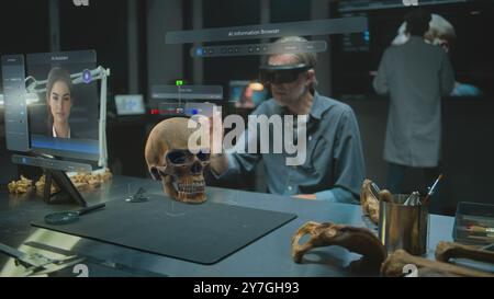 Fortgeschrittenes archäologisches Labor: Archäologe im VR-Headset untersucht fossilen Schädel und antike menschliche Anatomie mit Augmented Reality. 3D-Grafiken der virtuellen Anzeige mit KI-Assistent und Webbrowser. VFX Stockfoto