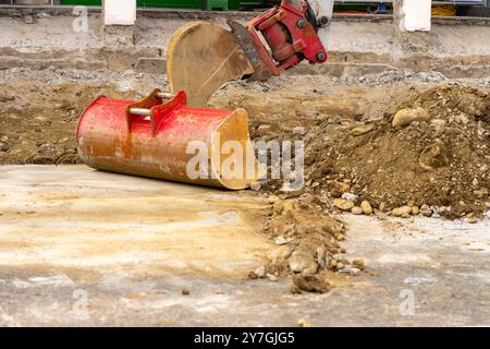 Baggerlöffel sammelt Erde und alten Asphalt auf einer Baustelle. Stockfoto