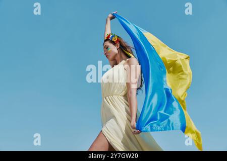 Attraktive ukrainische Frau mit Nationalflagge mit Himmel im Hintergrund Stockfoto
