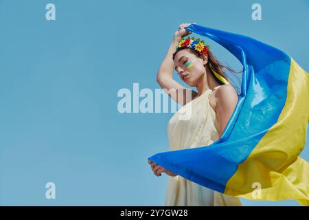 Schöne ukrainische Frau mit Nationalflagge mit Himmel im Hintergrund Stockfoto