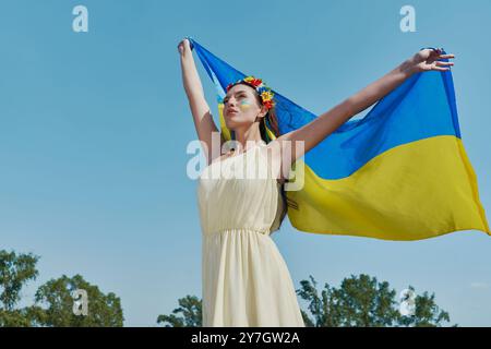 Schöne ukrainische Frau mit Nationalflagge mit Himmel im Hintergrund Stockfoto