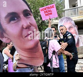 Jerusalem, Israel. 30. September 2024. Eine israelische Polizei versucht, Familien und Unterstützer israelischer Geiseln, die von der Hamas in Gaza festgehalten werden, mit Plakaten mit Fotos von Geiseln und Mitgliedern der israelischen Regierung bei einem Protest vor der Residenz des israelischen Premierministers Benjamin Netanjahu in Jerusalem am Montag, den 30. September 2024, zu stoppen. Die Demonstranten fordern, dass Netanjahu einen Deal zur Rückgabe der Geiseln an ihre Familien für Rosch Hashanah, das jüdische Neujahrsfest, das am 2. Oktober 2024 bei Sonnenuntergang beginnt. Demonstranten halten Premierminister Netanjahu persönlich verantwortlich für das Scheitern der Verhandlungen Stockfoto