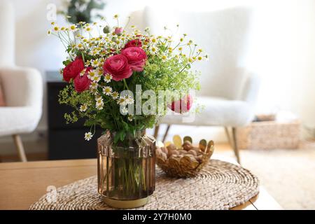 Wunderschöne Ranunkelblumen und Kamillen in Vase auf dem Tisch drinnen Stockfoto