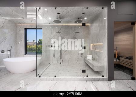 Modernes, luxuriöses Badezimmer mit großer Glasdusche, freistehender Badewanne und Sauna mit Marmorwänden und -Böden. Stockfoto
