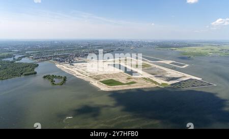 Der Bau von Häusern und Häusern auf der Center Island in Amsterdam IJburg hat begonnen. Es ist noch immer eine große Baustelle auf der zurückgewonnenen Insel. Der erste Bezirk wird im Frühjahr 2024 Gestalt annehmen. Ein wunderschöner bewölkter Himmel am klaren Horizont. ANP/ Hollandse Hoogte/ Aerovista Luchtfotografie niederlande aus - belgien aus Stockfoto