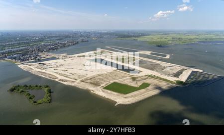 Der Bau von Häusern und Häusern auf der Center Island in Amsterdam IJburg hat begonnen. Es ist noch immer eine große Baustelle auf der zurückgewonnenen Insel. Der erste Bezirk wird im Frühjahr 2024 Gestalt annehmen. Ein wunderschöner bewölkter Himmel am klaren Horizont. ANP/ Hollandse Hoogte/ Aerovista Luchtfotografie niederlande aus - belgien aus Stockfoto