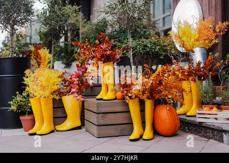 Halloween Dekoration mit Kürbissen und Gummistiefeln vor einem Blumenladen an einem Herbsttag. Stockfoto