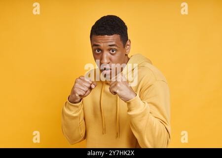 Selbstbewusster Mixed Race-Mann, der in Boxposition vor gelbem Hintergrund steht Stockfoto