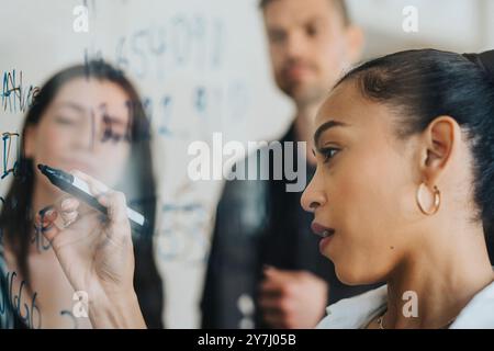 Geschäftsfrau schreibt Statistiken auf Glasplatte im Büro Stockfoto