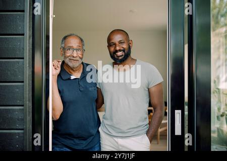 Porträt eines lächelnden Mannes, der neben dem Vater steht, in der Tür des Hauses Stockfoto