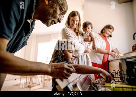 Junge, der Utensilien im Geschirrspüler von Großvater zu Hause lädt Stockfoto