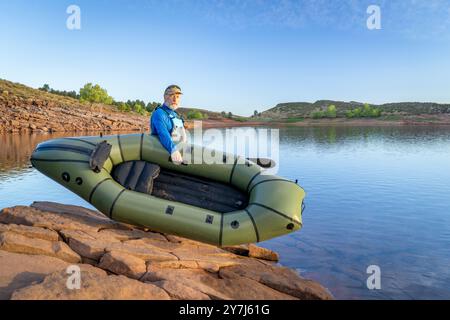 Senior männlicher Paddler startet ein aufblasbares Packboot an einem Ufer des Horsetooth Reservoir in Colorado Stockfoto