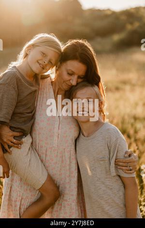 Frau mit Armen um Söhne, die auf der Wiese stehen Stockfoto