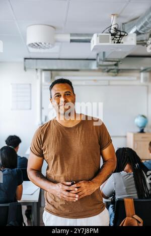 Porträt eines lächelnden, selbstbewussten männlichen Professors, der im Klassenzimmer an der Junior High School steht Stockfoto