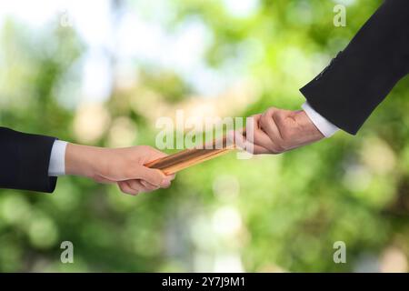 Geschäftsmann übergibt Staffelstab an Kollegen draußen, Nahaufnahme Stockfoto
