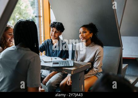 Gruppe multirassischer Schüler, die mit Laptop in der Cafeteria an der Junior High School studieren Stockfoto