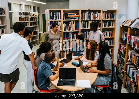Hochwinkelansicht der Lehrerschaft von männlichen und weiblichen Schülerinnen in der Bibliothek des Sekundarschulstudiums Stockfoto