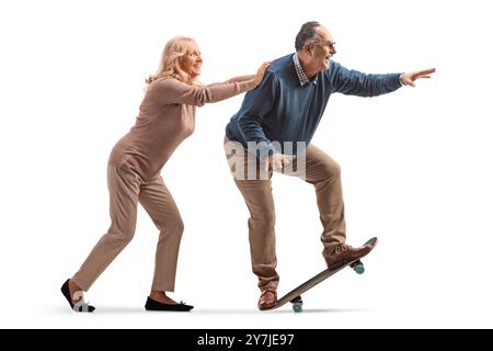 Profilaufnahme einer Frau, die einen Mann mittleren Alters auf einem Skateboard schießt, isoliert auf weißem Hintergrund Stockfoto