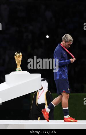 Peking, China. Dezember 2022. Dieses Foto, das am 18. Dezember 2022 aufgenommen wurde, zeigt Antoine Griezmann aus Frankreich, wie er seine Silbermedaille ansieht, während er während der Trophäenzeremonie an der Trophäe der FIFA-Weltmeisterschaft vorbeiläuft, nachdem Frankreich das finale Fußballspiel der Weltmeisterschaft in Katar 2022 zwischen Argentinien und Frankreich im Lusail-Stadion in Lusail, nördlich von Doha verlor. Atletico Madrid Stürmer Antoine Griezmann gab am Montag bekannt, dass er mit Frankreich aus dem internationalen Fußball ausscheiden werde. Quelle: Lan Hongguang/Xinhua/Alamy Live News Stockfoto