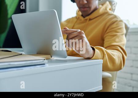 Nahaufnahme eines multirassischen Mannes, der ein digitales Tablet benutzt, während er an seinem Arbeitsplatz sitzt Stockfoto