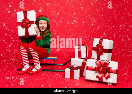 Schöne attraktive Heiter Heiter froh aufgeregt lustig vor - jugendlich elf Sitzen auf dem Schlitten Holding in den Händen fairy Wunder Tradition kaufen möchten im Winter Stockfoto