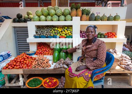 Eine Frau, die frisches Gemüse und Obst im Entebbe Market in Uganda verkauft Stockfoto