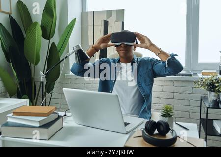 Junger Mann mit einer Virtual-Reality-Brille, während er am Arbeitsplatz sitzt Stockfoto