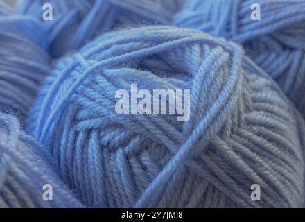 Nahaufnahme Blauer Garnball mit weichem Fokus. Abstrakter Hintergrund und Textur für Design. Warmes Wollgarn im Hintergrund. Strickhobbyarbeit. Strickmuster. Stockfoto