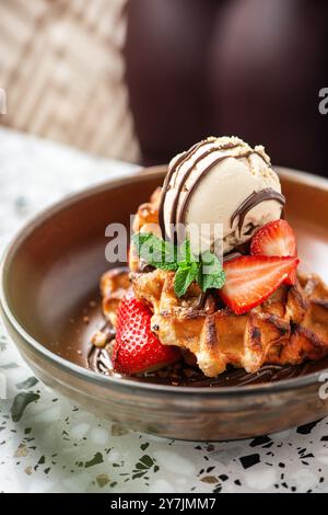 Amerikanische Waffeln mit Eis, Erdbeeren, Ahornsirup und Zartbitterschokolade. Stockfoto