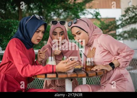 Drei Freunde sind in einem Café, um Inhalte auf einem Mobilgerät zu teilen Stockfoto