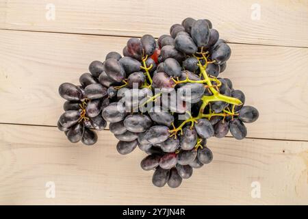 Ein Haufen reifer schwarzer Trauben auf einem Holztisch, Makro, Blick von oben. Stockfoto