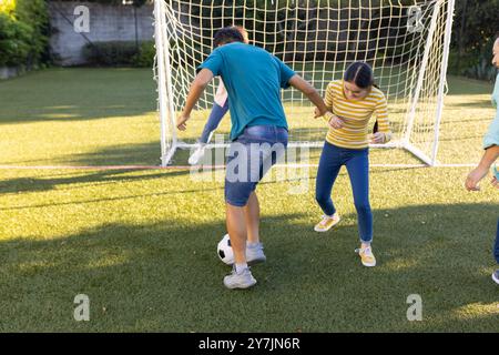 Fußball spielen, Familie Outdoor-Aktivitäten auf dem Rasenplatz in der Nähe des Torpfosten genießen Stockfoto