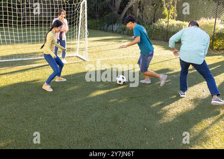 Fußball spielen auf dem Feld, Familie genießen Outdoor-Aktivitäten gemeinsam im Park Stockfoto