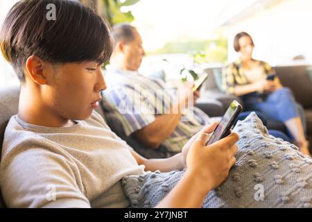 Mit Smartphones, Familienmitgliedern, die auf der Couch sitzen und sich auf den Bildschirm konzentrieren Stockfoto