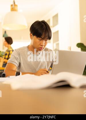 Mit Laptop, junger Mann, der sich auf die Arbeit am Heimbüro konzentriert Stockfoto