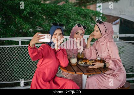 Freunde genießen eine Mahlzeit und nehmen Selfies in einer gemütlichen Caf-Umgebung Stockfoto