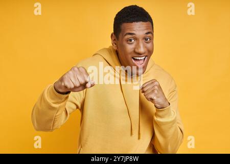 Ein verspielter Mann mit gemischter Rasse, der in einer Pose vor gelbem Hintergrund steht Stockfoto