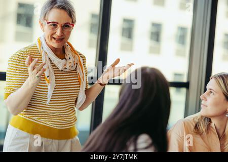 Ein leitender Dozent interagiert mit Studenten in einem Klassenzimmer in der Stadt und fördert eine ansprechende und dynamische Bildungsatmosphäre, die auf interaktive Inhalte ausgerichtet ist Stockfoto