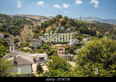 Balkanlandschaft der Hügelstadt mit schöner Architektur. Gebäude auf dem Hügel zwischen grünen Bäumen im albanischen Gjirokaster. Stockfoto