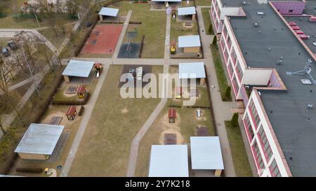 Luftaufnahme eines Kindergartenspielplatzes mit verschiedenen Spielstrukturen und überdachten Bereichen. Stockfoto