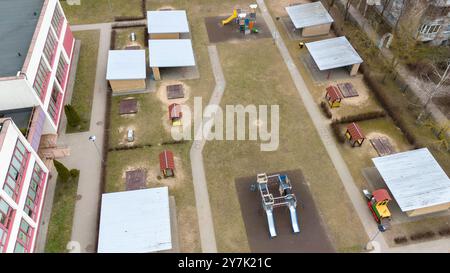 Luftaufnahme eines Kindergartenspielplatzes mit verschiedenen Spielstrukturen und überdachten Bereichen. Stockfoto