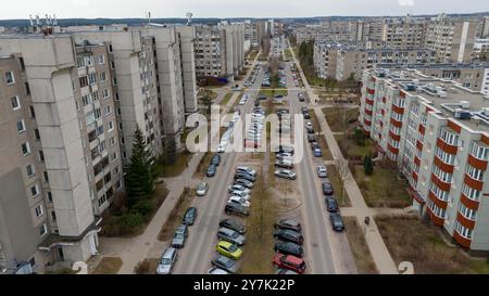 Blick aus der Vogelperspektive auf eine Wohngegend mit großen Appartementhäusern auf beiden Seiten einer breiten Straße. Die Straße ist gesäumt von geparkten Autos und Bäumen, Stockfoto