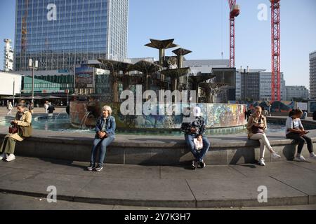 Die Menschen genießen die Morgensonne beim Volksbrunnen und seinem Graffiti auf dem Alexanderplatz, dem Brunnen der Völkerfreundschaft Stockfoto