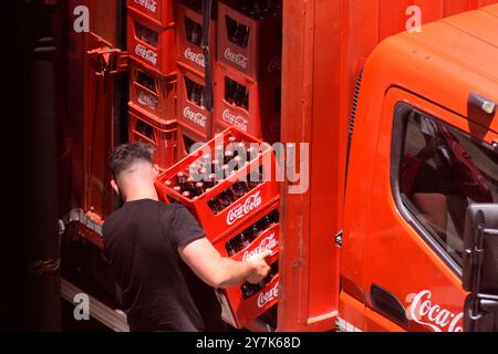 Coca-Cola-Liefermann, der Flaschenkisten in einer Straße von San Lorenzo de El Escorial in der Gemeinde Madrid nimmt. Stockfoto