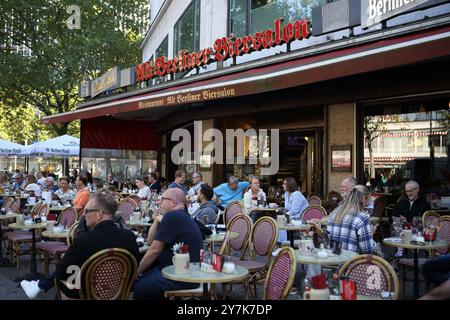 Die Aufnahmen gegen die Sonnenkamera halten Silhouetten fest, die auf dem Bürgersteig am Kurfürstendamm laufen, einer Hauptgeschäftsstraße in Berlin Stockfoto