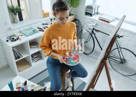 Blick von oben auf die schöne junge Frau, die Farben beim Zeichnen im Kunststudio mischt Stockfoto